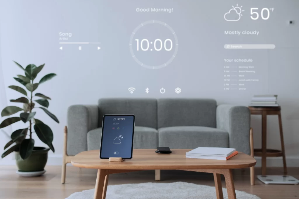 A modern living room in an Indian apartment featuring smart home technology with a tablet control panel, projected digital interface on the wall displaying time, weather, and schedules, showcasing seamless smart home automation integration.
